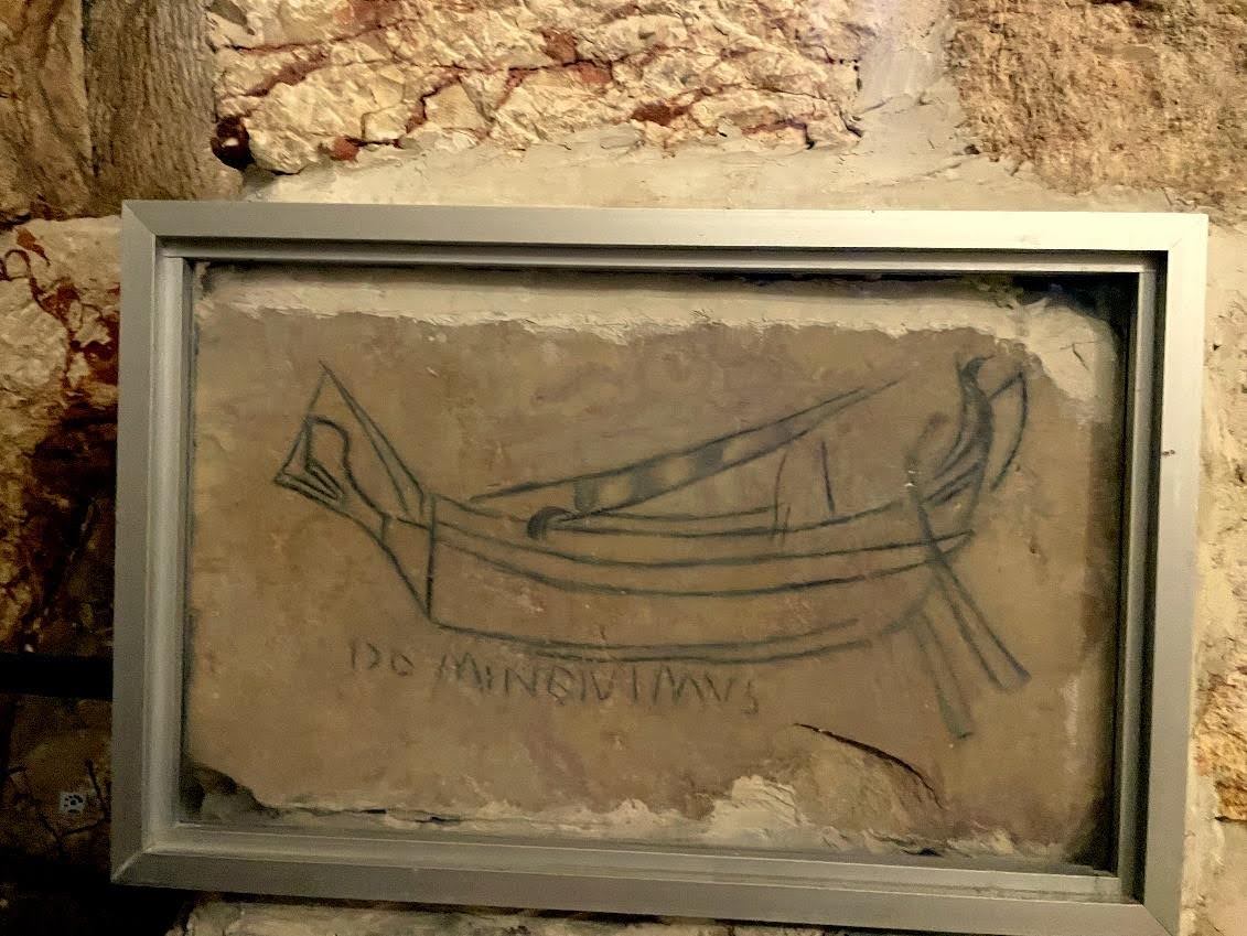 To preserve it better, the famous inscription has been placed under glass. The prow of the ship is on the left and the stern on the right. Note the double steering oar. If the author of the graffito respected the proportions more or less, it would be a modest merchant ship typical of the Roman Mediterranean. Photo: Henri Gourinard.